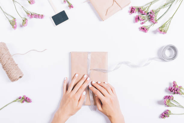 istock Female hands wrapping holiday gifts on a white table 862209828