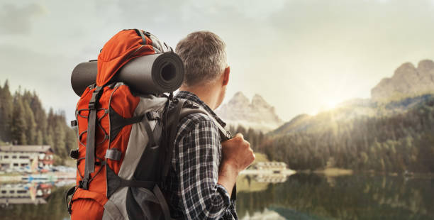Hiker trekking on the mountains and contemplating the panorama, he is carrying a backpack and hiking equipment, sports and nature concept