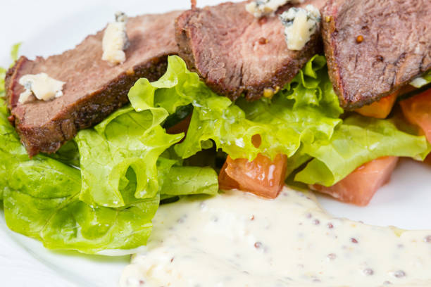 Veal pieces with vegetables and mayonnaise sauce on white background
