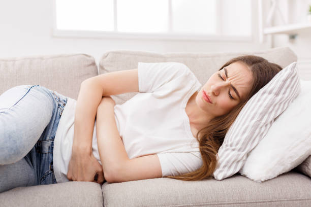 istock Young girl suffering from stomachache lying down on sofa 862217876
