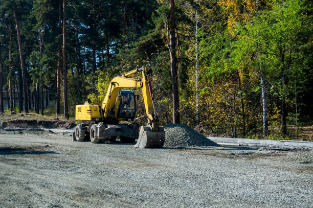 Road repair, asphalt laying. Yellow wheeled excavator on the background of the forest.