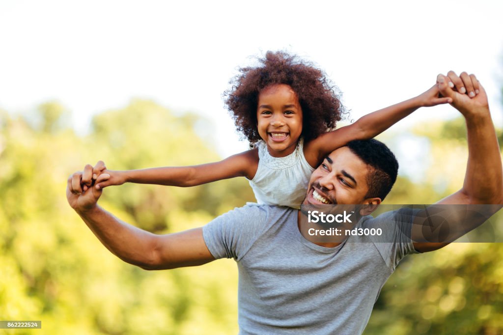 Retrato de joven padre llevando a su hija en su espalda - Foto de stock de Padre libre de derechos