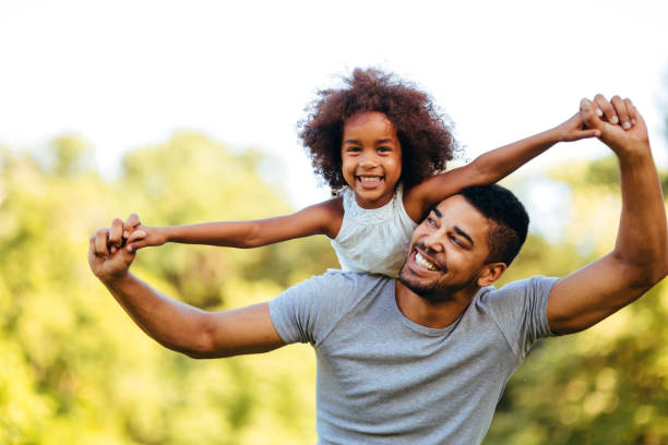 Portrait of young father carrying his daughter on his back Portrait of young father carrying his daughter on his back in nature father and daughter stock pictures, royalty-free photos & images