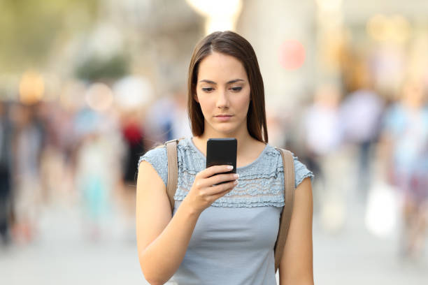 Serious girl checking phone message on the street