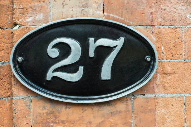 Number 27 metal plate on a brick wall