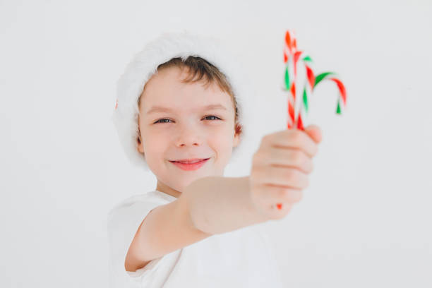 istock Boy in red Santa hat holding a candy cane 862244280