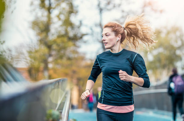 female athlete running outdoors - city life audio imagens e fotografias de stock