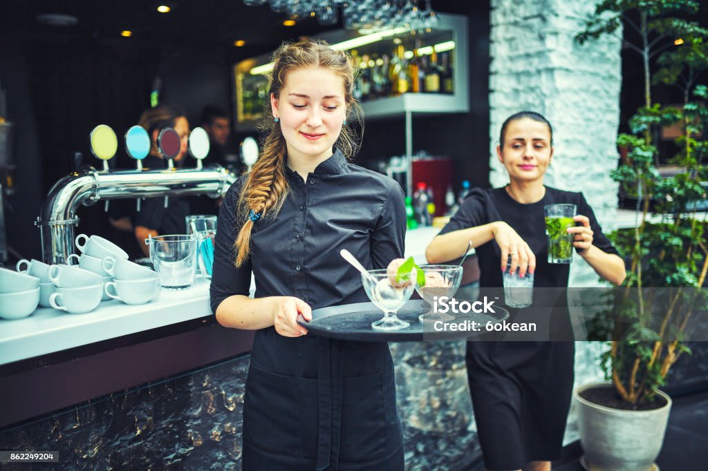 Waiters carrying plates with food, in a restaurant. Waiters carrying plates with meat dish at a wedding. Food And Drink Industry Stock Photo