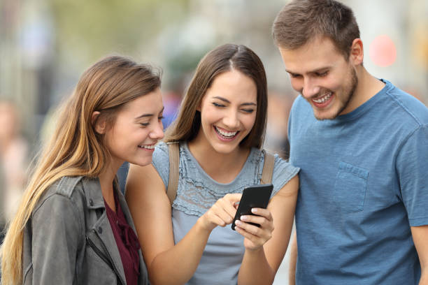 istock Three friends checking smart phone content on the street 862250858