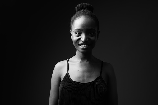 Studio shot of young beautiful African Zulu woman wearing black sleeveless top with hair bun in black and white horizontal shot