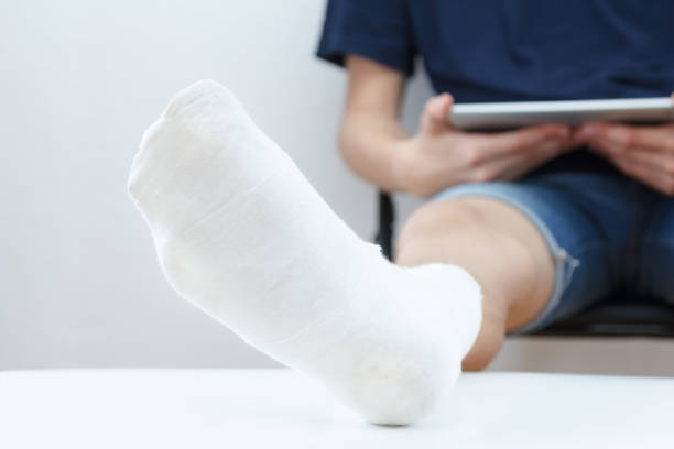istock Man with broken leg in a plaster with tablet on white background 862262014