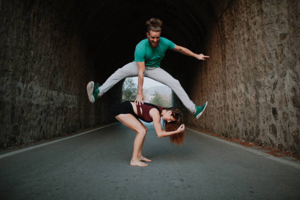 saltar de homem pulando de mulher em uma estrada. - leapfrog - fotografias e filmes do acervo