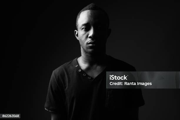 Photo libre de droit de Prise De Vue Studio Du Jeune Homme Africain Porte Chemise Noire En Noir Et Blanc banque d'images et plus d'images libres de droit de Image en noir et blanc