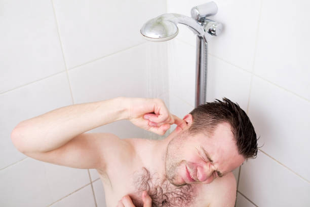 uomo caucasico che si pulisce l'orecchio mentre fa la doccia e sta sotto l'acqua che scorre. - men naked water male foto e immagini stock