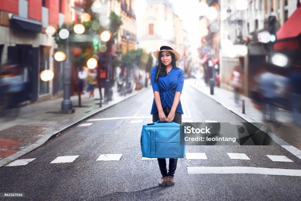 Mulher asiática sorridente usando chapéu e mala de exploração - Foto de stock de Adulto royalty-free