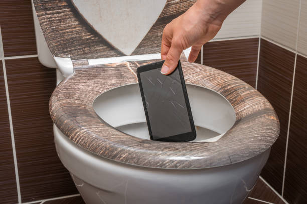 女性の便器に携帯電話を投げて - mobile phone smart phone toilet water ストックフォトと画像