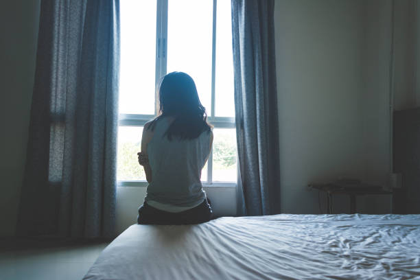 istock woman sitting on bed in room with light from window 862285852