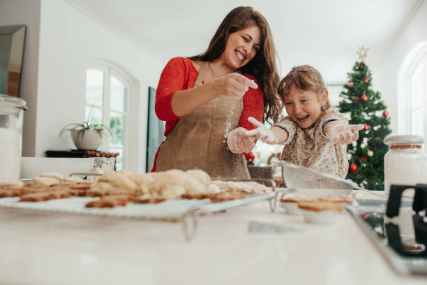 mãe e filha se divertindo ao fazer biscoitos de natal. - holiday cookies - fotografias e filmes do acervo