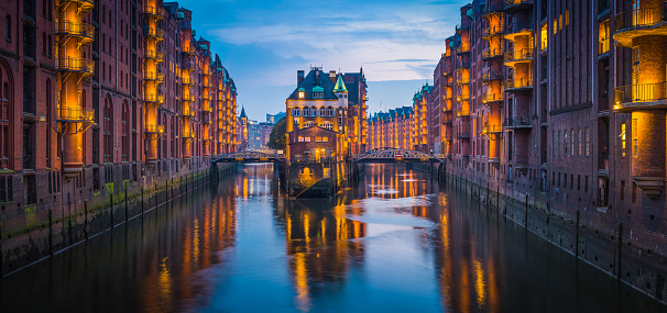 Warm lamplight illuminating the historic UNESCO World Heritage Site of Speicherstadt, City of Warehouses, district in the heart of Hamburg, Germany’s vibrant second city.