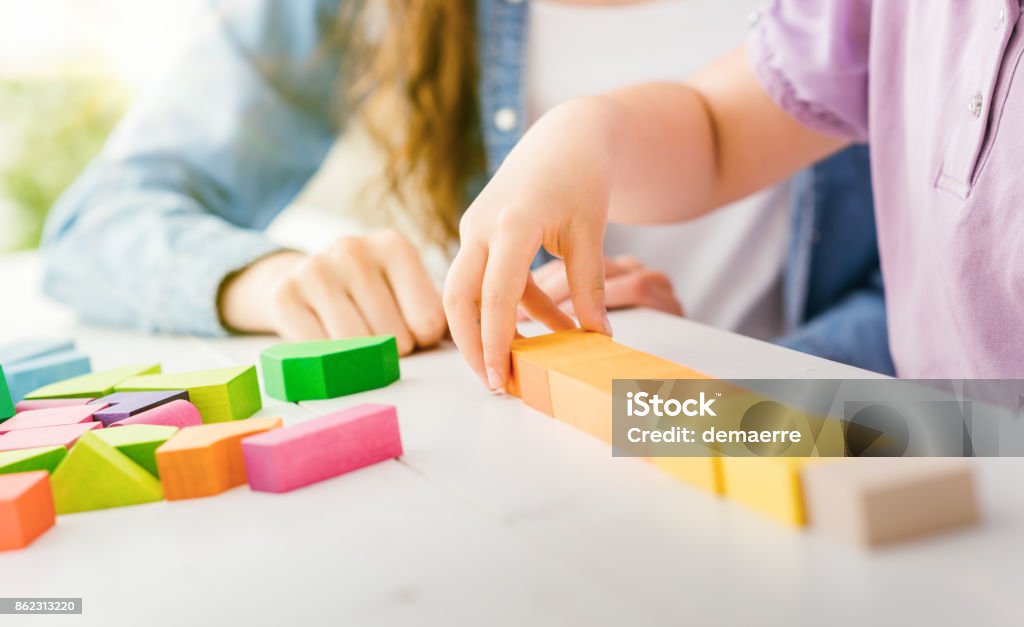 Child playing with wood blocks Girl playing with colorful toy wood blocks, her mother is helping her, education and fun concept Nanny Stock Photo