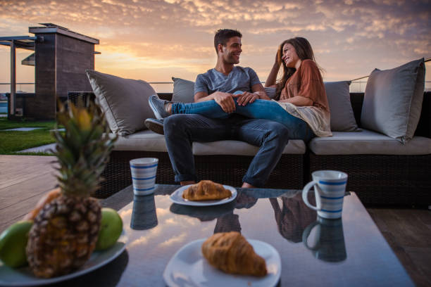 istock Young happy couple talking on sofa at penthouse patio. 862313514