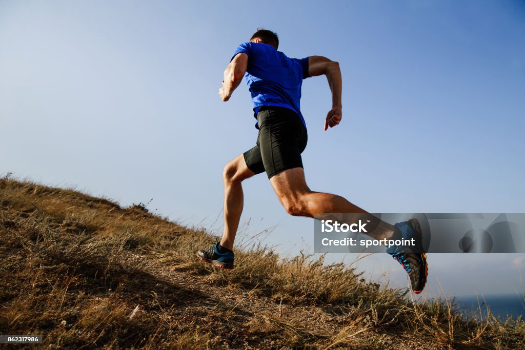 dinâmica de corrida em ladeiras na trilha atleta masculino corredor lado vista - Foto de stock de Correr royalty-free