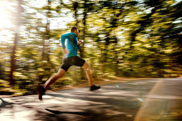 istock blurred motion male runner running on forest road in sunlight 862318024