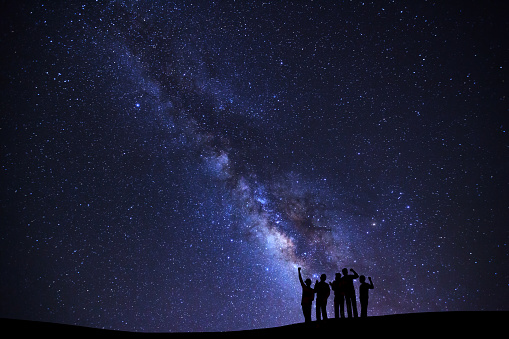 Landscape with milky way galaxy, Starry night sky with stars and silhouette of people standing happy man on high mountain.