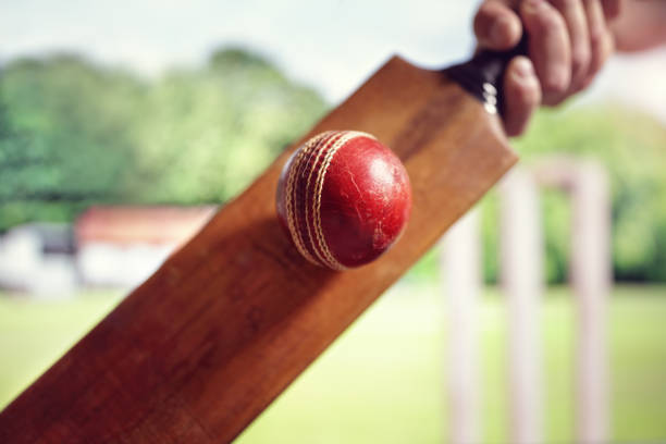 Cricket player hitting ball Cricket batsman hitting a ball shot from below with stumps on cricket pitch game swing stock pictures, royalty-free photos & images