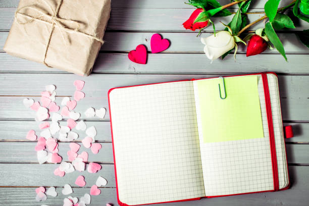 istock rose flowers close-up with gift box, hearts and blank note book on wooden background. Spring summer border template. mockup floral background. sale, greeting and celebration card concept. 862345132