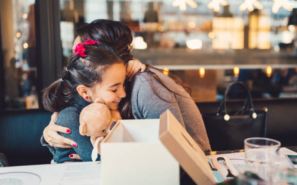 Mother and daughter celebrating a birthday together Cute girl in restaurant receiving a birthday gift from her mother childrens day photos stock pictures, royalty-free photos & images