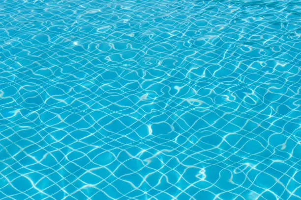 Blue and bright water surface with sunreflection in swimming pool