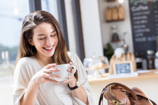 istock Cheerful young woman studies coffee cup during coffee break 862360132