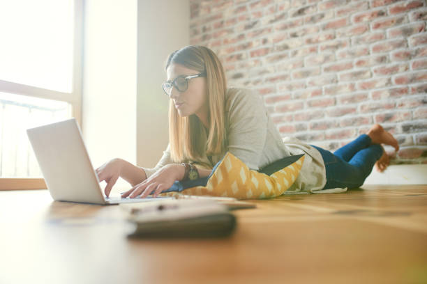 istock Serious woman lying on the floor and using laptop 862375958