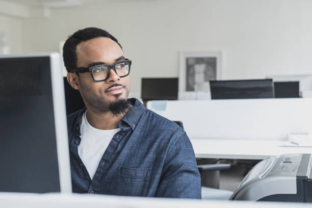 istock Pensive young man wearing glasses in office looking away 862378556
