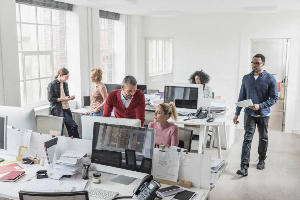 Busy multi racial office with people talking and working in bright interior