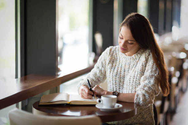 istock Beautiful woman sitting in restaurant and writing 862385136