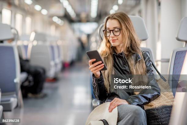 Mujer Montando En El Tren Moderno Foto de stock y más banco de imágenes de Tren - Tren, Viajes, Usar el teléfono