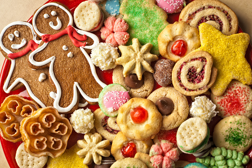 A colorful and festive plate of Christmas Cookies. Still life photographed on wooden table with copy space.