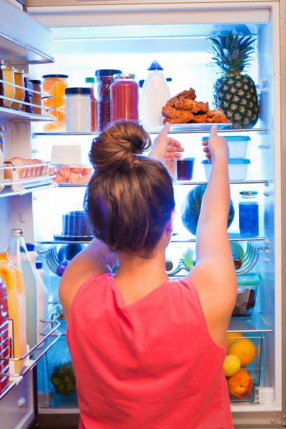 istock Young Woman Making Decision on Unhealthy Eating in Front of Refrigerator 862400702