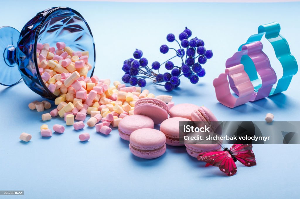 marshmallow and macaroons pouring out of jars. blue background. marshmallow and macaroons pouring out of jars. blue background. selective focus. Brown Stock Photo