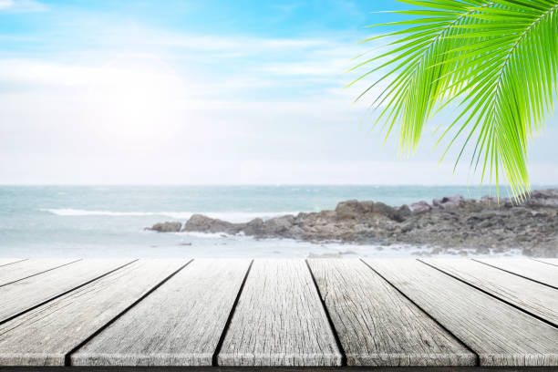istock Empty wooden table and palm leafs with party on beach background blurred. 862404028