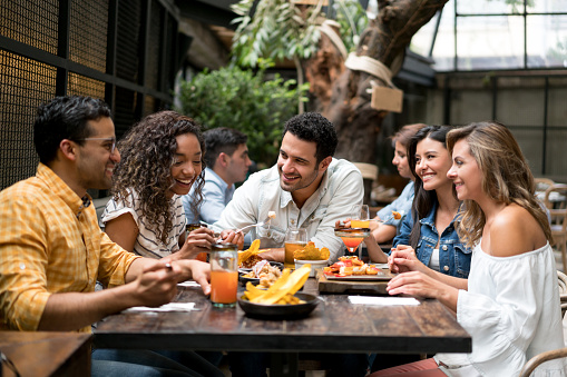 Happpy group of friends having dinner together at a restaurant and having fun - lifestyle concepts