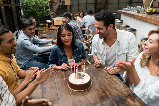 Portrait of a happy Latin American woman celebrating her birthday with a group of friends at a restaurant
