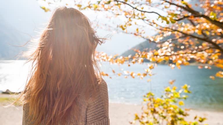 Woman at lakeside in autumn looking in the distance