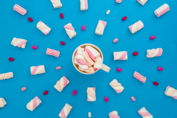 istock Marshmallow and candy with cappuccino mug on blue background. Flat lay, top view 862415650