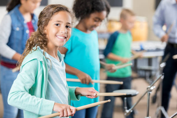 istock Smiling schoolgirl plays drums during percussion class 862416186