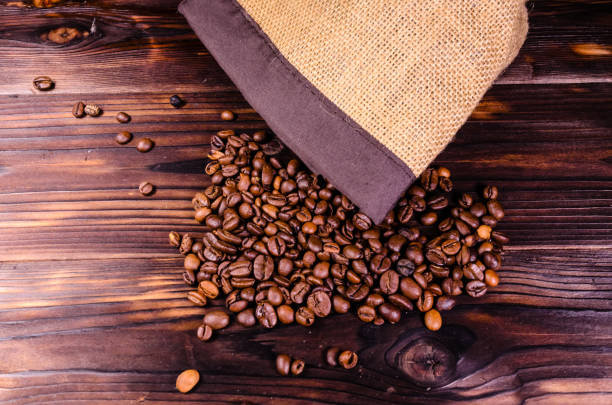 istock Roasted coffee beans in sack on wooden table. Top view 862416220