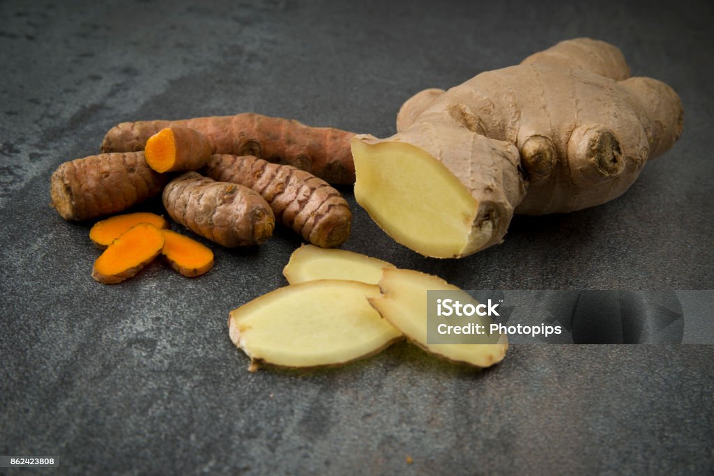 turmeric slices and ginger root sliced turmeric slices and ginger root sliced on gray background Ginger - Spice Stock Photo