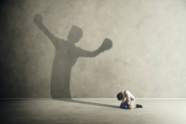 man defeated by his shadow boxing stock photo